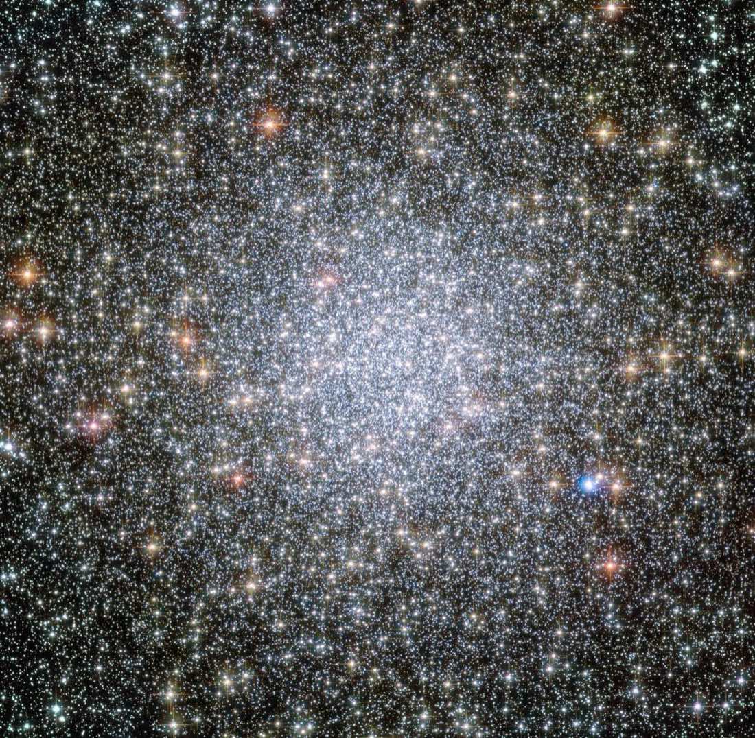 A dense ball of countless stars, white at the centre with scattered gold and blue