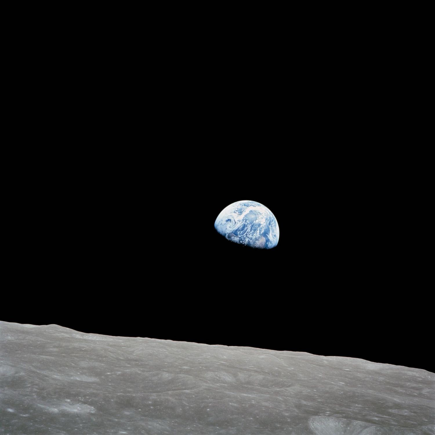 Earthrise: the blue and white Earth rising above the grey edge of the Moon, against black space