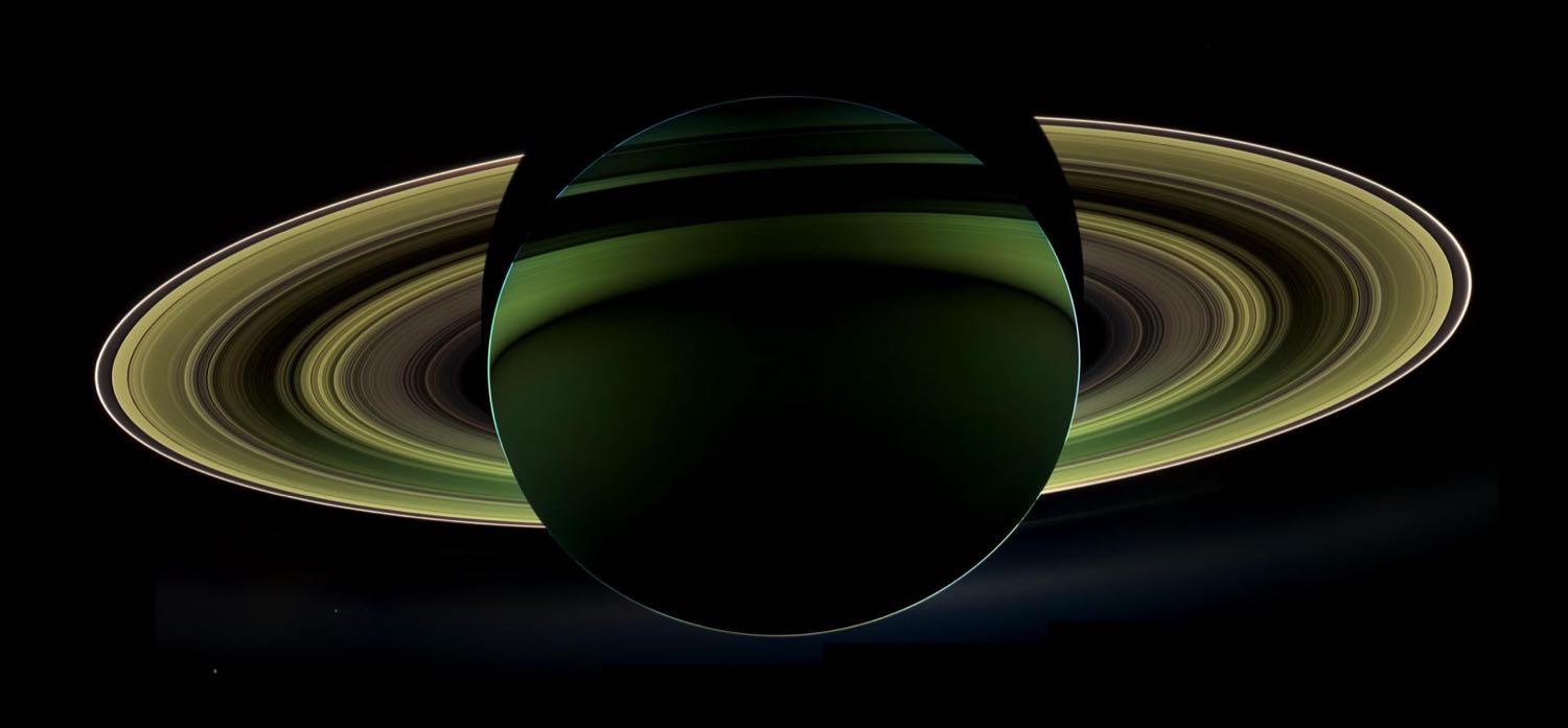 Saturn seen from behind, a dark globe with its rings lit up in a thin bright ellipse