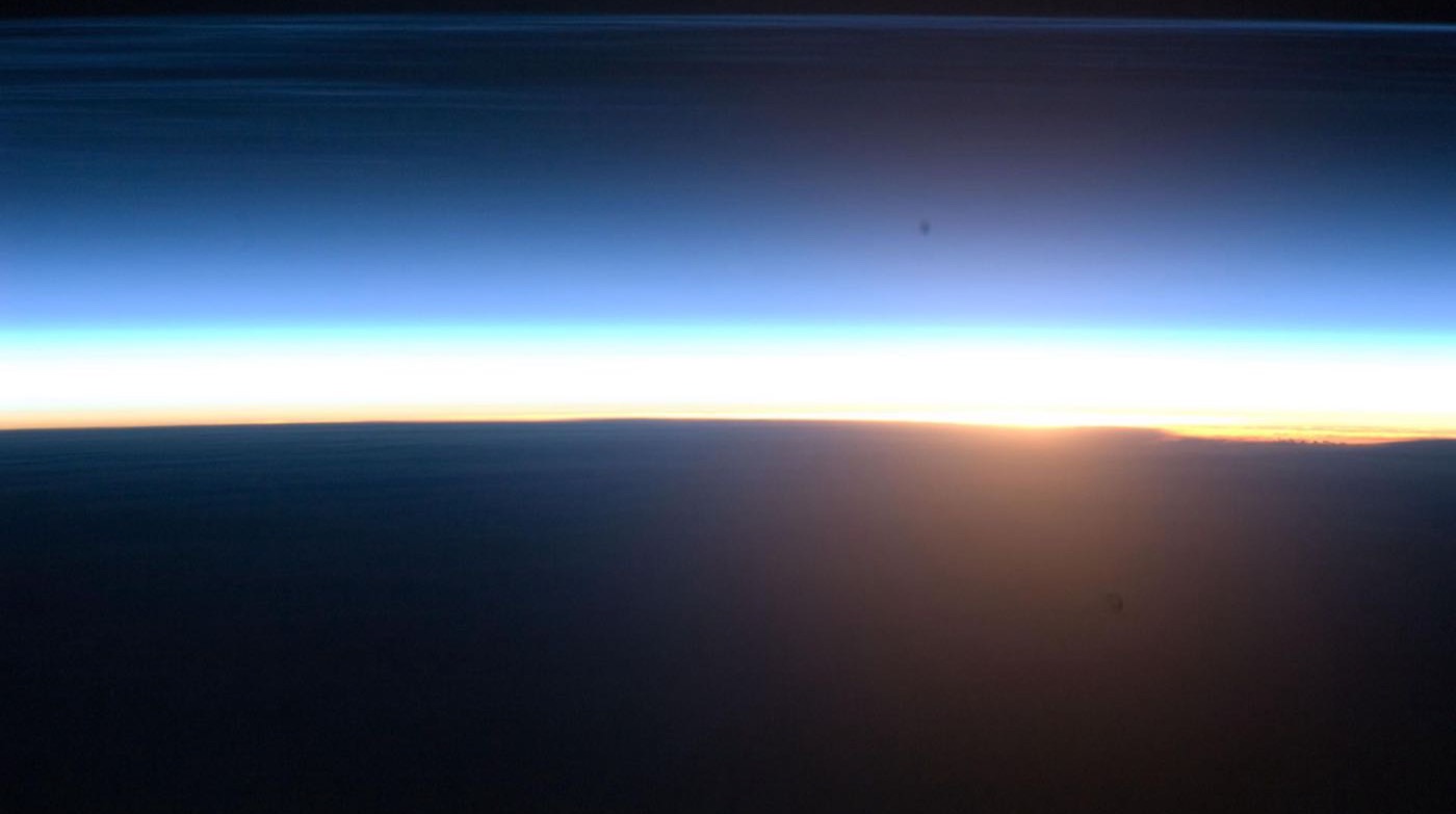 Sunrise seen from orbit: a thin bright band of light along the curve of the dark Earth
